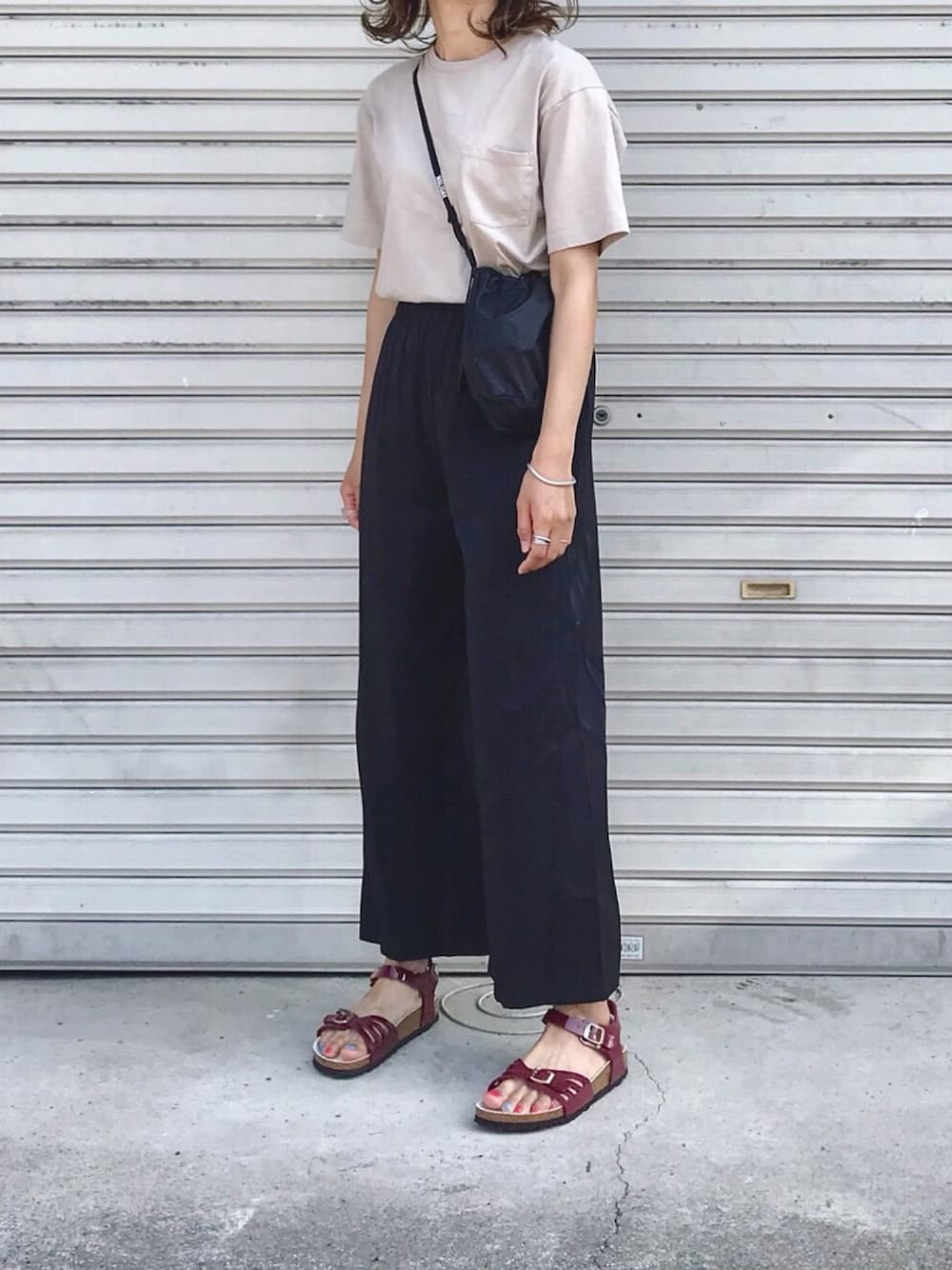 レッド系のサンダル、ブラック系のその他パンツ、ベージュ系のTシャツ/カットソーを着用したレディースの夏コーディネートの1枚目の写真