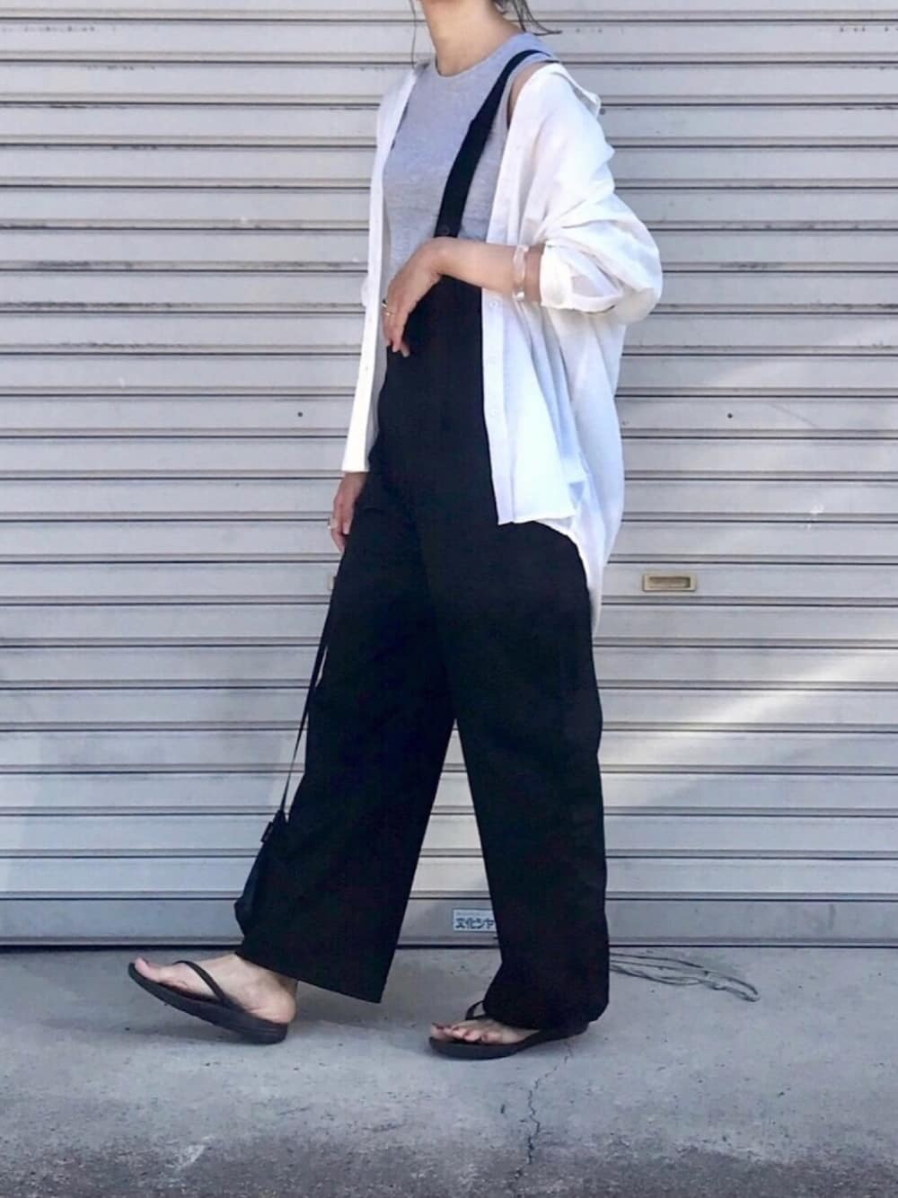 ホワイト系のシャツ/ブラウス、ブラック系のサロペット/オーバーオール、ブラック系のサンダルを着用したレディースの夏コーディネートの1枚目の写真