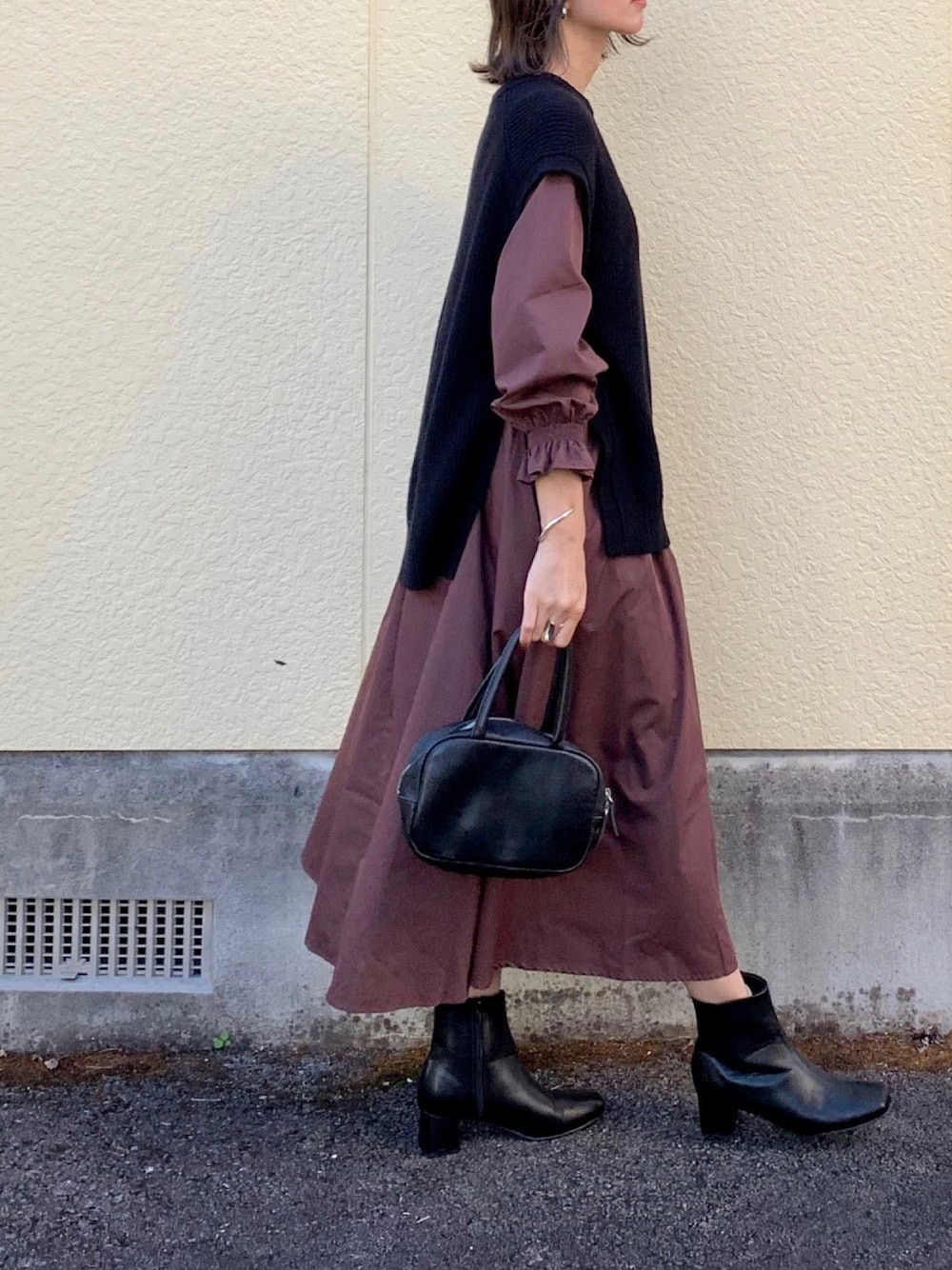 ブラウン系のワンピース、ブラック系のニット/セーター、ブラック系のブーツを着用したレディースの秋コーディネートの1枚目の写真