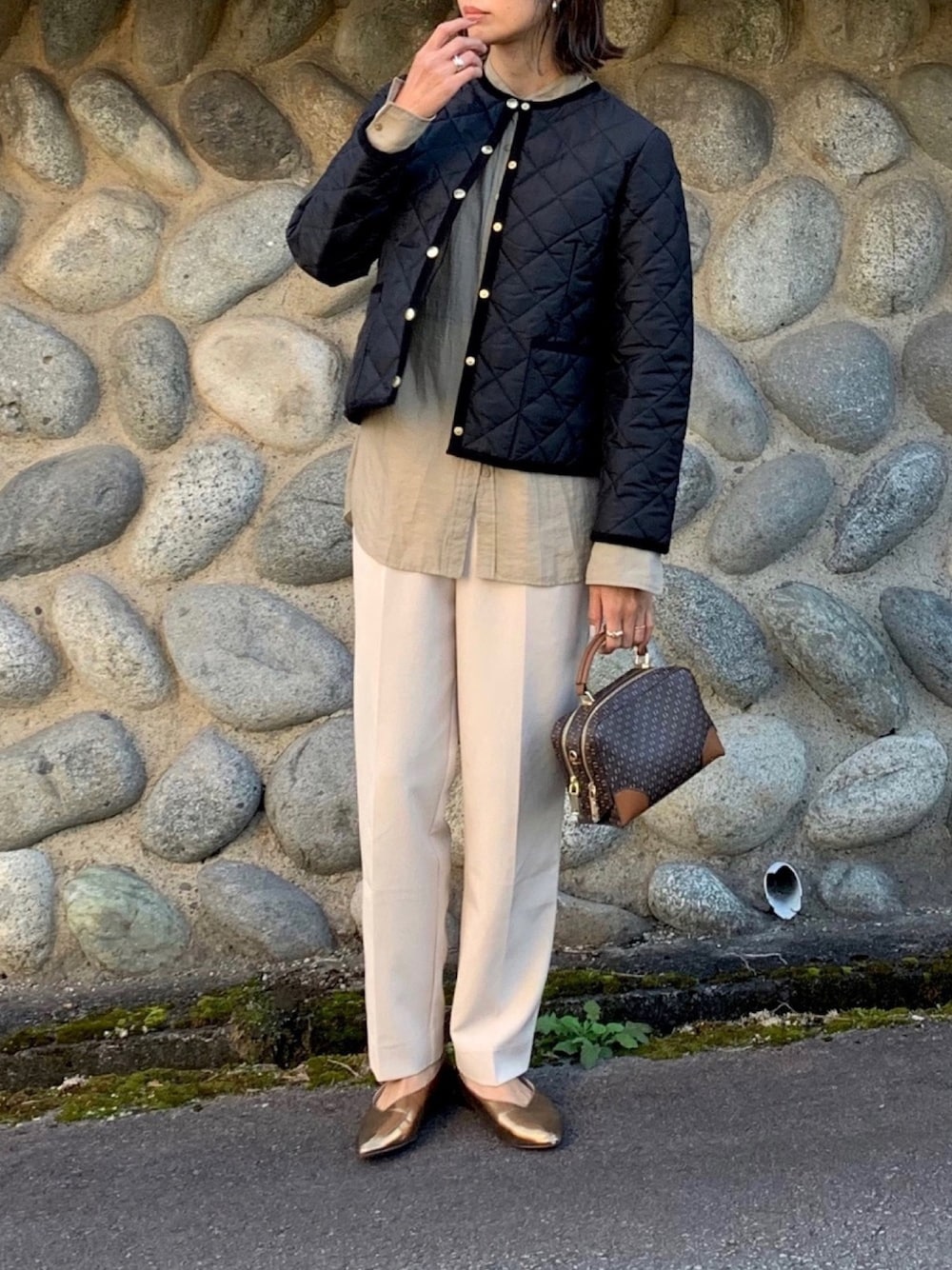 ブラック系のノーカラージャケット、ベージュ系のTシャツ/カットソー、ブラウン系のショルダーバッグを着用したレディースの秋コーディネートの1枚目の写真