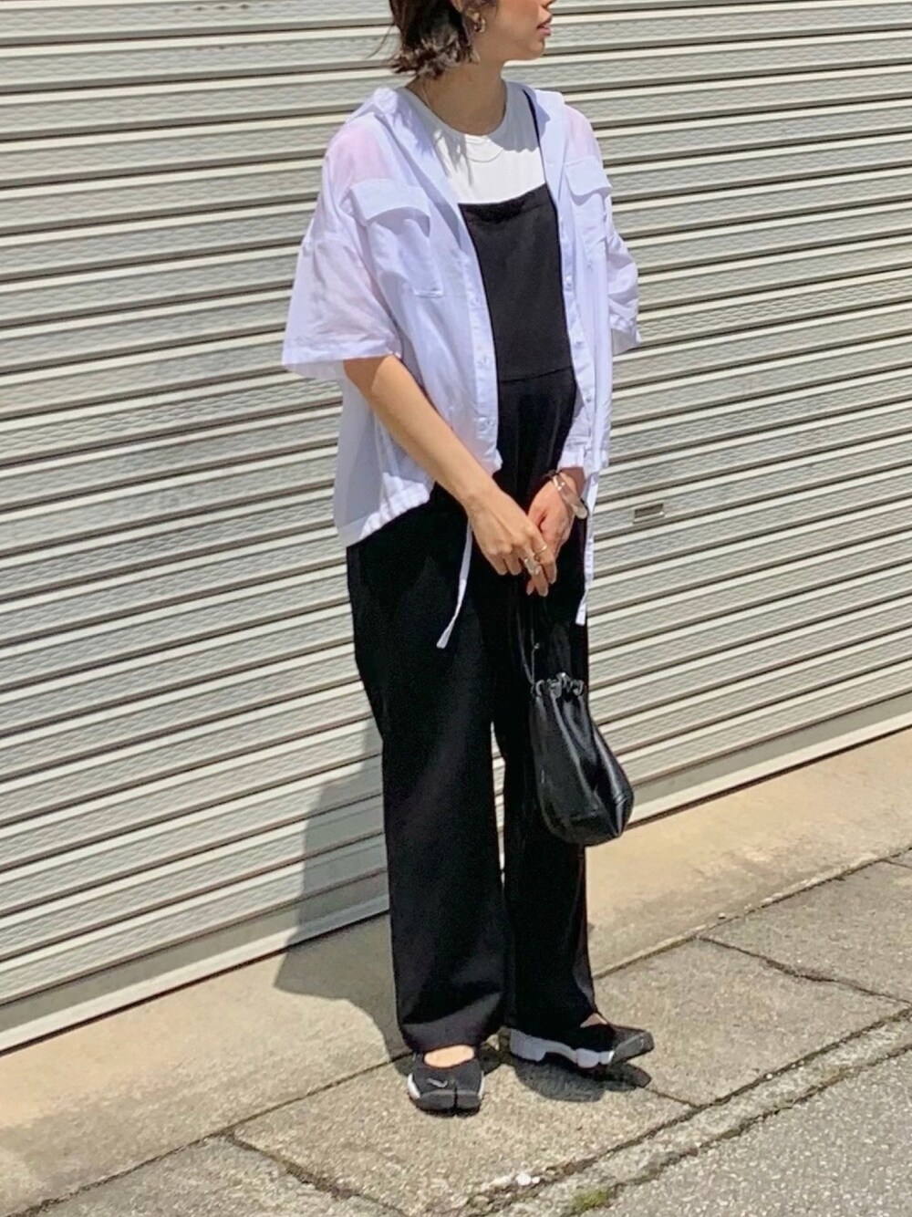 ホワイト系のシャツ/ブラウス、ブラック系のサロペット/オーバーオール、ブラック系のスニーカーを着用したレディースの春コーディネートの1枚目の写真