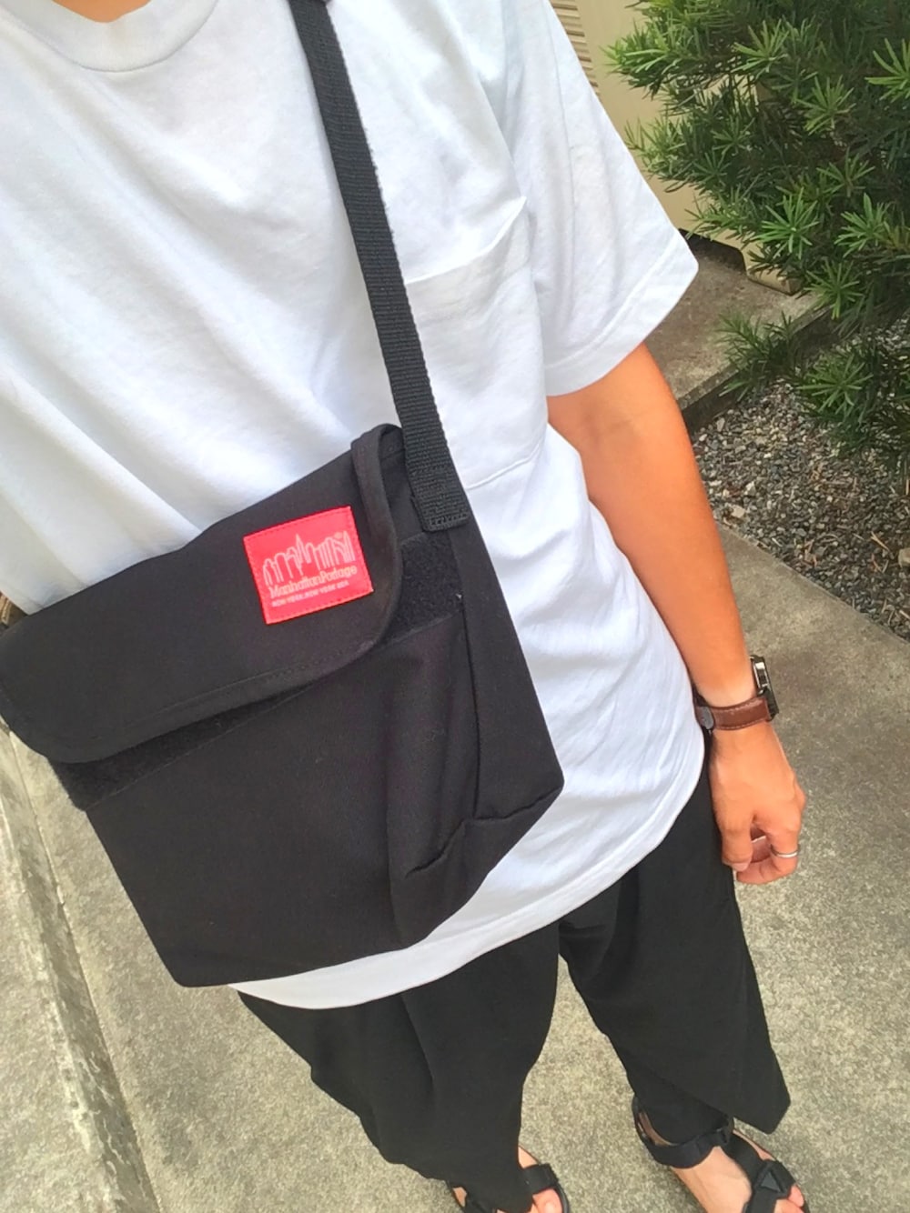 ホワイト系のTシャツ/カットソー、ブラック系のスラックス、ブラック系のサンダルを着用したメンズの夏コーディネートの1枚目の写真