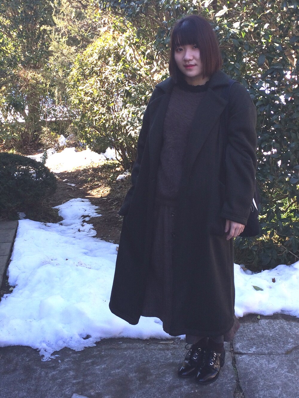 ブラウン系のニット/セーター、ブラック系のTシャツ/カットソー、ブラウン系のスカートを着用したレディースの冬コーディネートの1枚目の写真