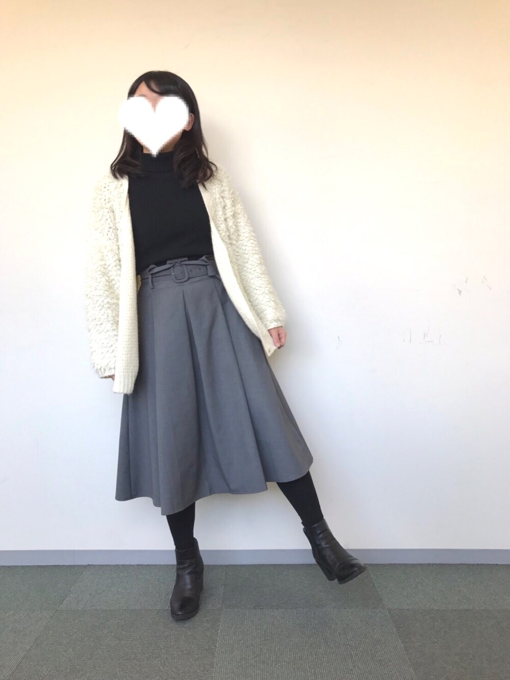ホワイト系のカーディガン/ボレロ、ブラック系のニット/セーター、グレー系のスカートを着用したレディースの冬コーディネートの1枚目の写真