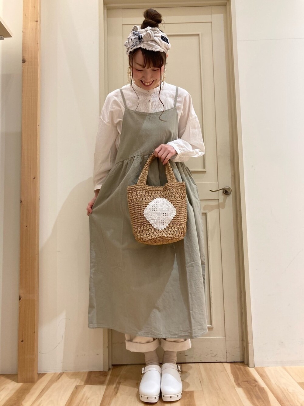 ホワイト系のシャツ/ブラウス、グリーン系のワンピース、ホワイト系のデニムパンツを着用したレディースの春コーディネートの1枚目の写真