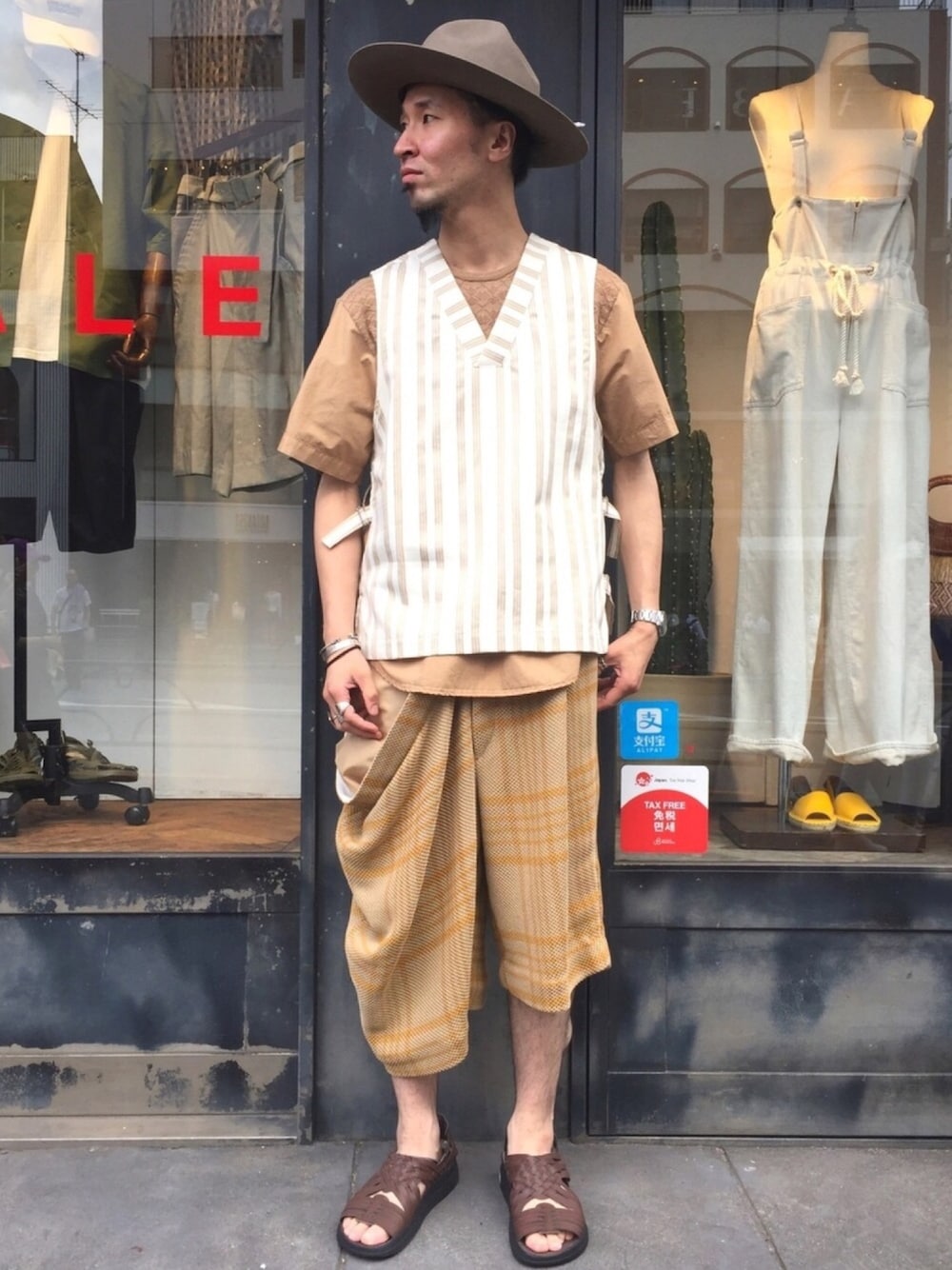 ベージュ系のベスト、ベージュ系のパンツ、ブラウン系のサンダルを着用したメンズの夏コーディネートの1枚目の写真