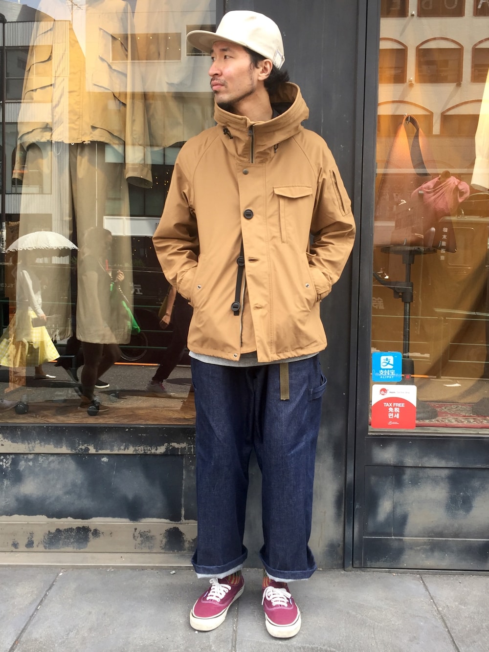 イエロー系のマウンテンパーカー、ブルー系のデニムパンツ、レッド系のスニーカーを着用したメンズの秋コーディネートの1枚目の写真