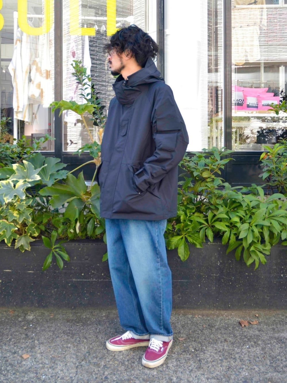 ブラック系のマウンテンパーカー、ブルー系のデニムパンツ、レッド系のスニーカーを着用したメンズの秋コーディネートの1枚目の写真