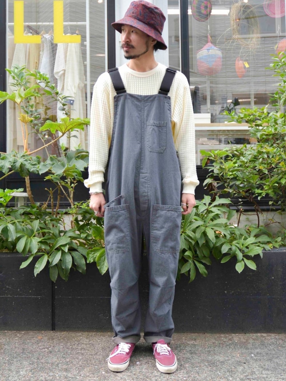 グレー系のオールインワン・サロペット、ホワイト系のTシャツ/カットソー、レッド系のスニーカーを着用したメンズの秋コーディネートの1枚目の写真