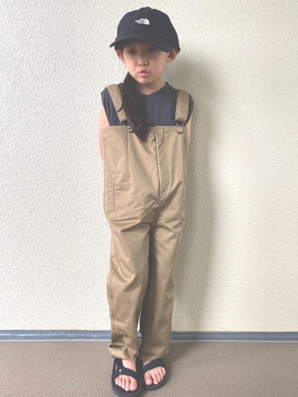 グレー系のTシャツ/カットソー、ベージュ系のサロペット/オーバーオール、ブラック系のサンダルを着用したキッズの夏コーディネートの1枚目の写真