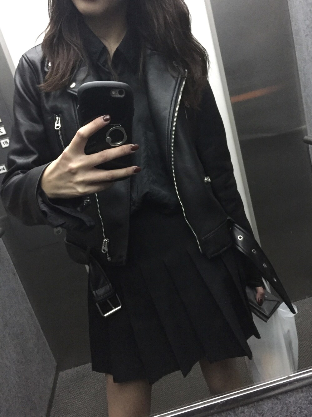 ブラック系のライダースジャケット、ブラック系のスカートを着用したレディースの秋コーディネートの1枚目の写真