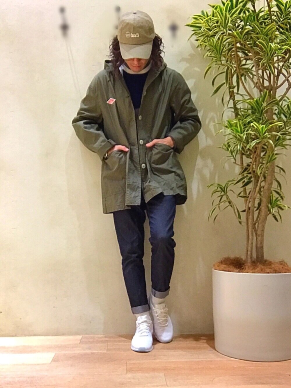 グリーン系のステンカラーコート、ホワイト系のスニーカー、ブルー系のデニムパンツを着用したメンズの冬コーディネートの1枚目の写真