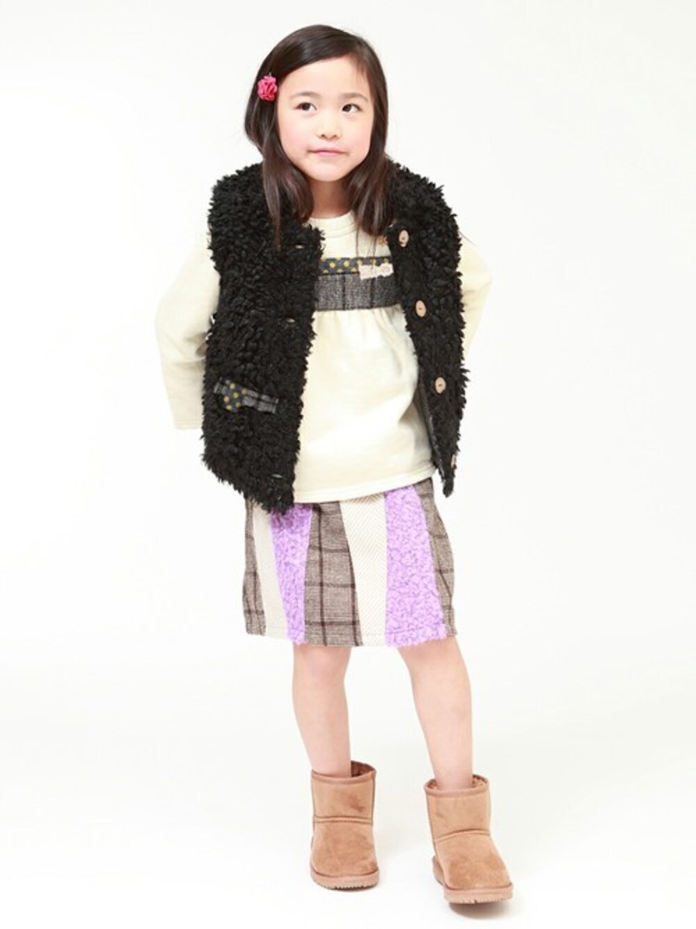 ブラック系のベスト、ホワイト系のスウェット、パープル系のスカートを着用したキッズの冬コーディネートの1枚目の写真