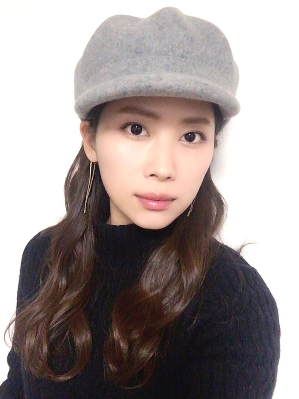 ブルー系のニット/セーター、グレー系のキャスケット、ゴールド系のピアス（両耳用）を着用したレディースの冬コーディネートの1枚目の写真