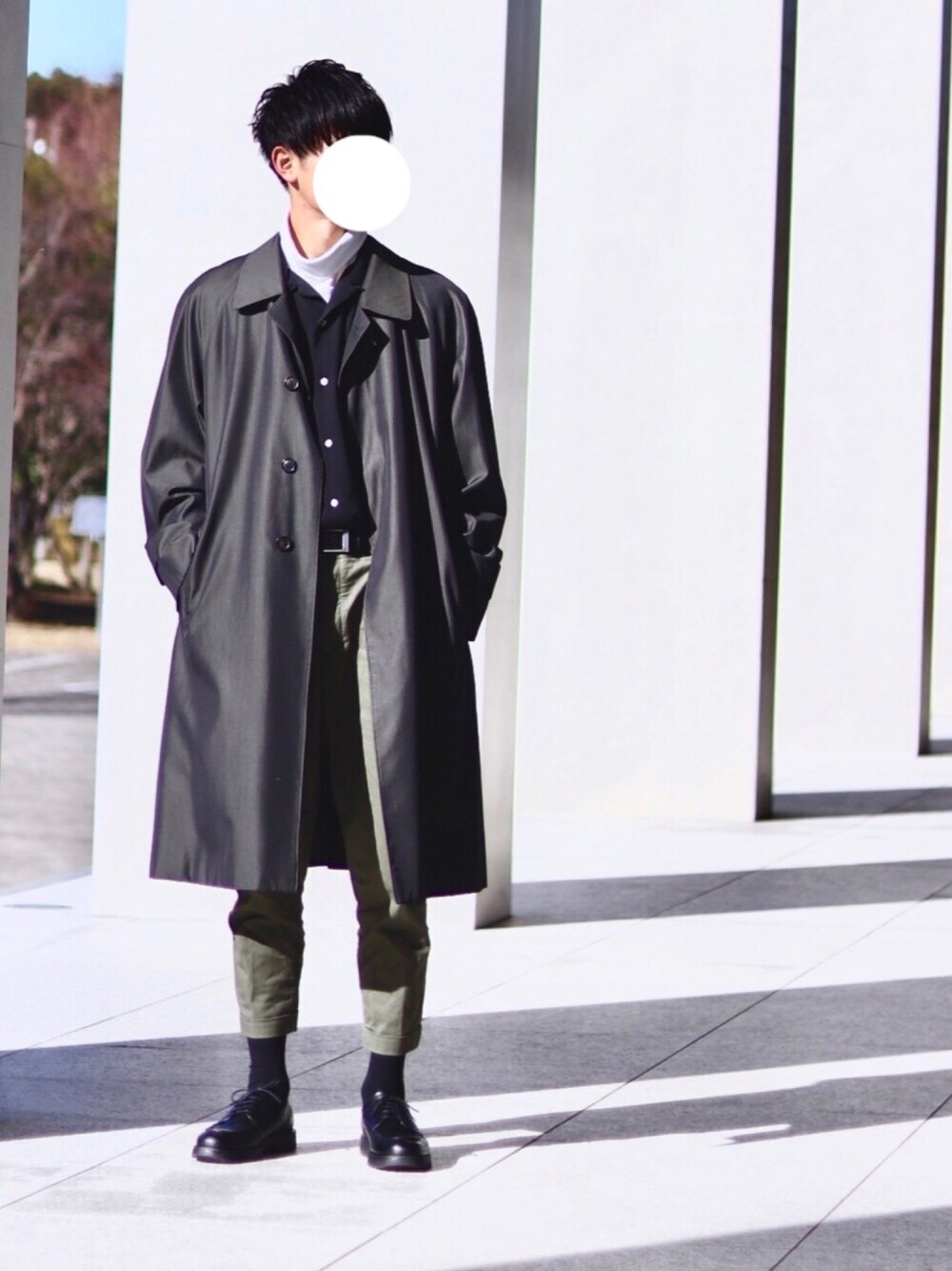 ブラック系のステンカラーコート、ブラック系のシャツ/ブラウス、グリーン系のチノパンツを着用したメンズの冬コーディネートの1枚目の写真