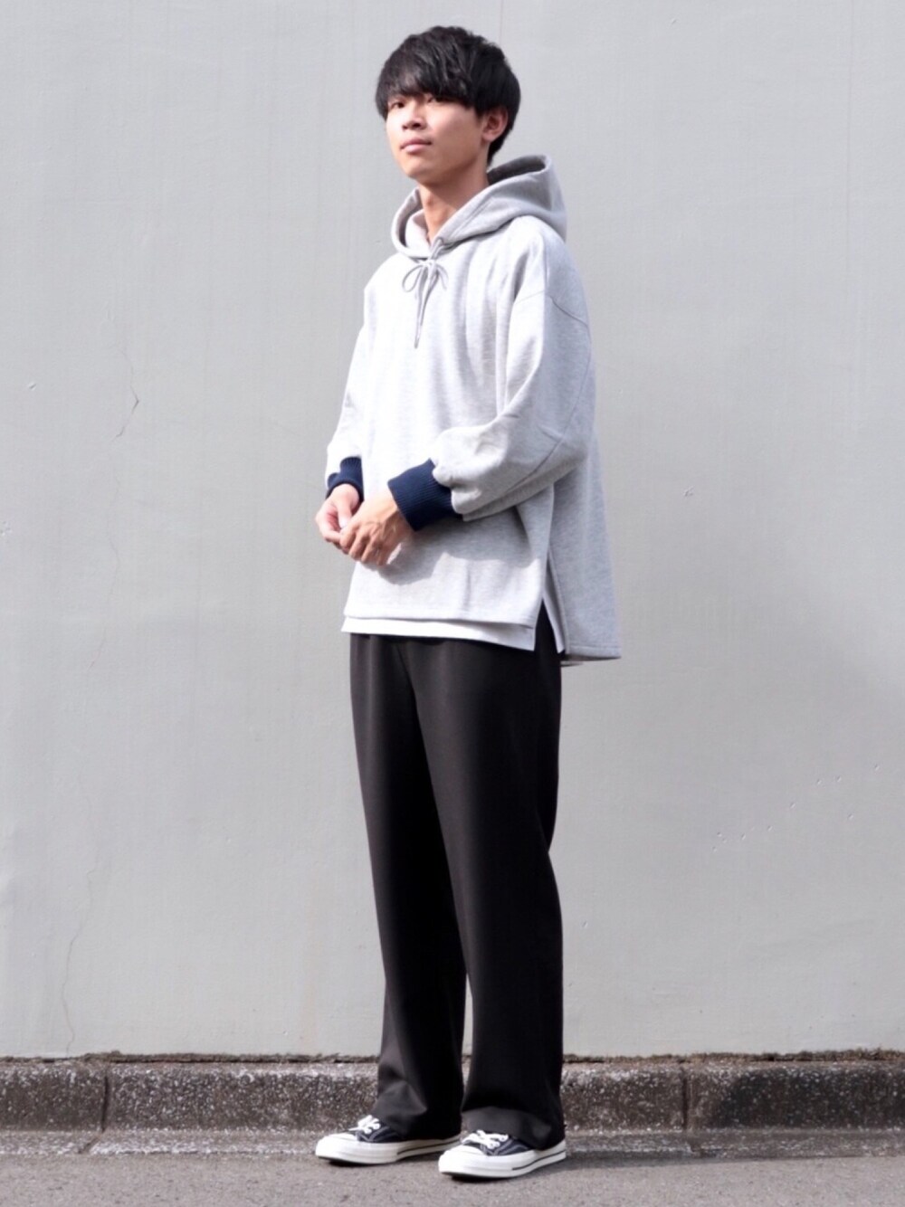 グレー系のパーカー、ホワイト系のタンクトップ、ブラック系のスラックスを着用したメンズの秋コーディネートの1枚目の写真