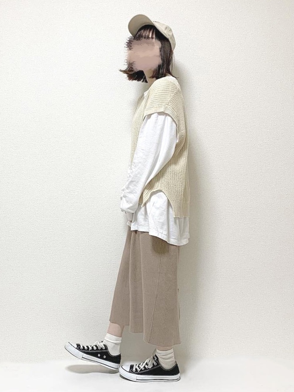 ホワイト系のニット/セーター、ベージュ系のスカート、ブラック系のスニーカーを着用したレディースの春コーディネートの1枚目の写真