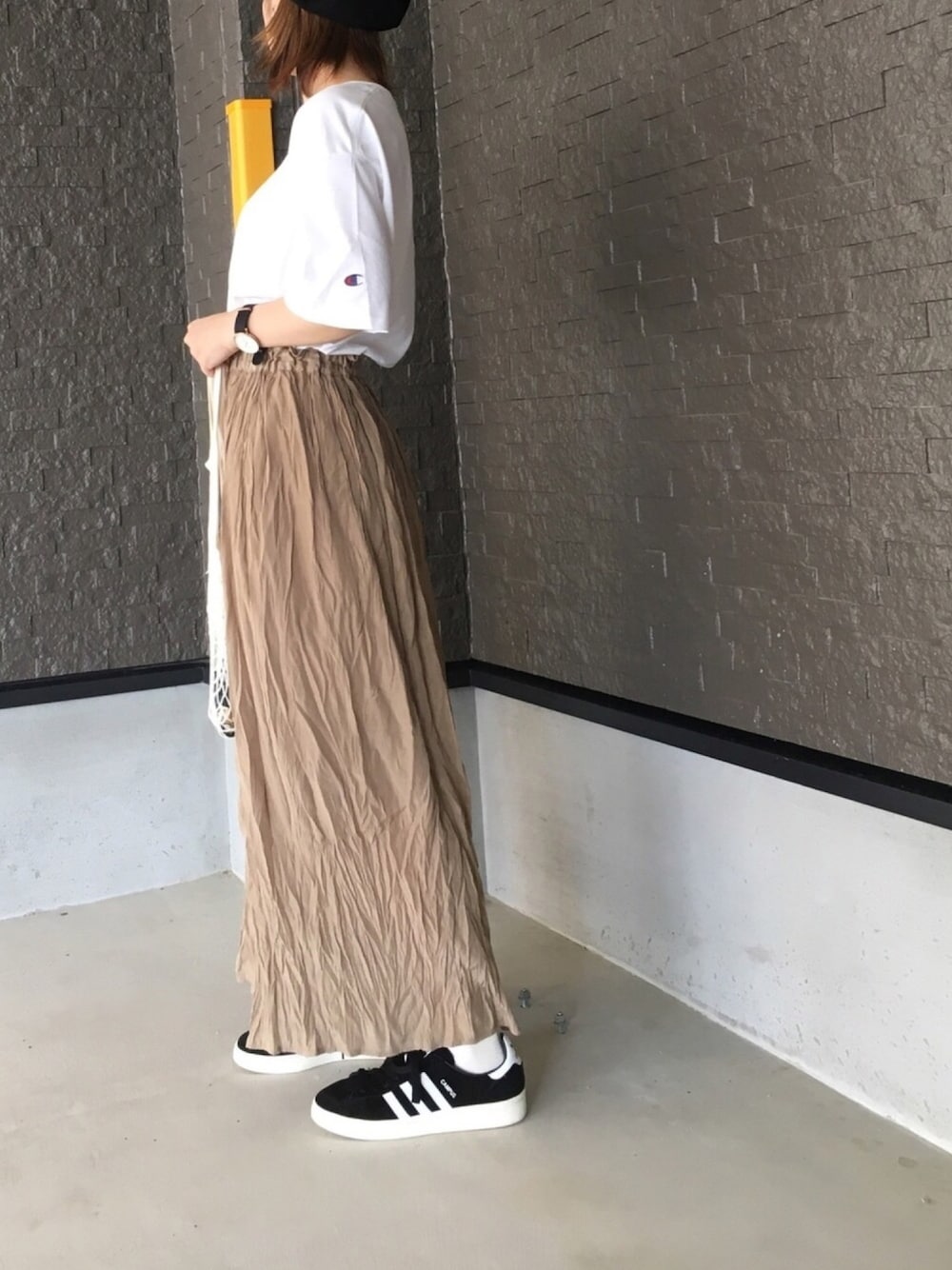 ホワイト系のTシャツ/カットソー、ベージュ系のスカート、ブラック系のスニーカーを着用したレディースの秋コーディネートの1枚目の写真