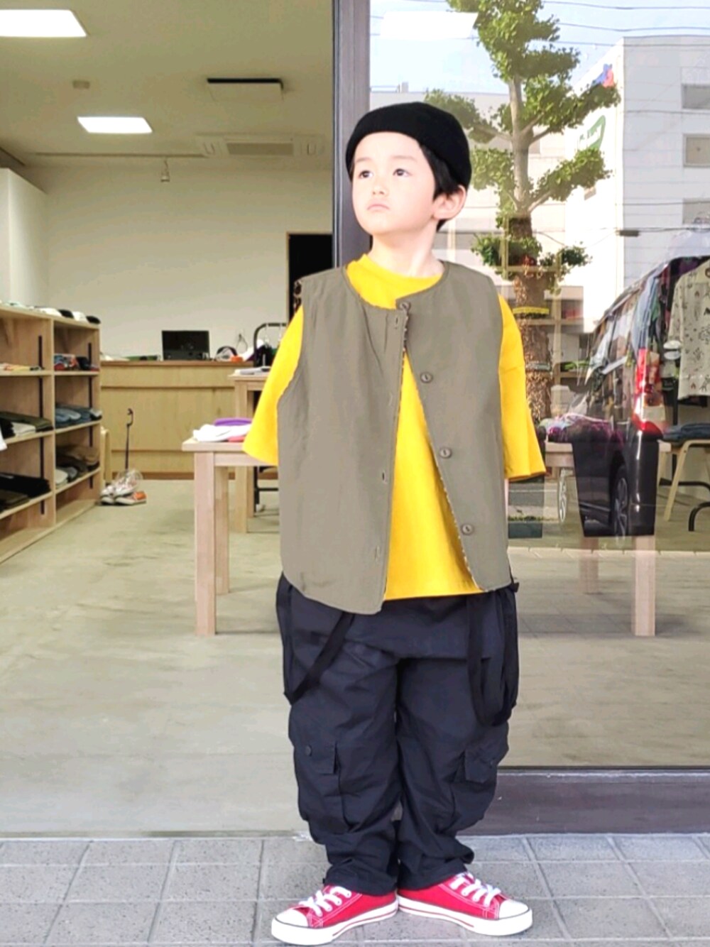 グリーン系のベスト、ブラック系のパンツ、イエロー系のTシャツ/カットソーを着用したキッズの春コーディネートの1枚目の写真