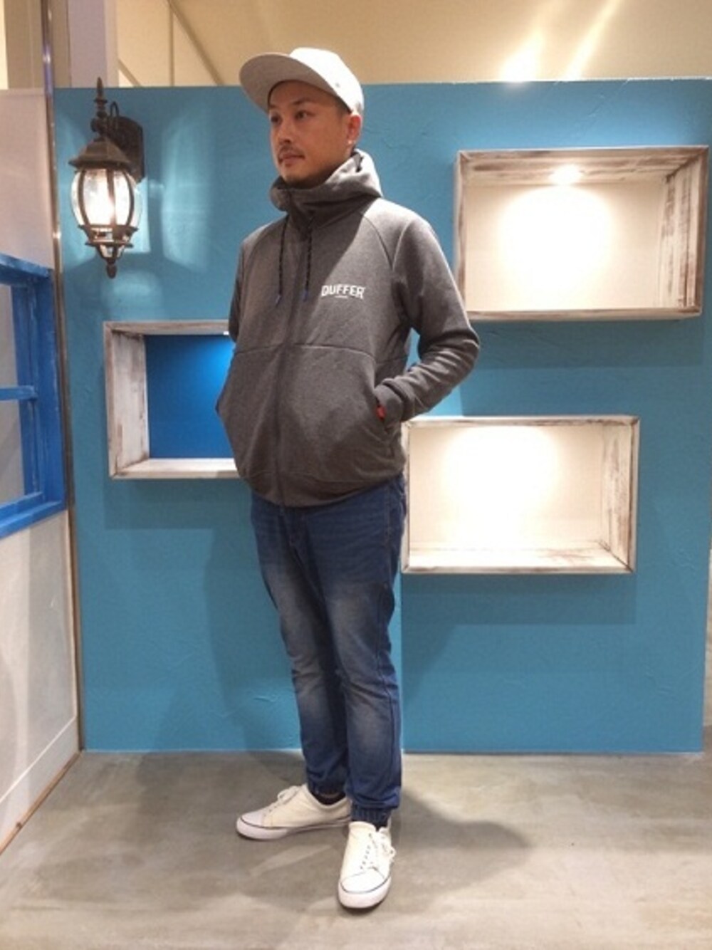 グレー系のパーカー、ホワイト系のスニーカーを着用したメンズの春コーディネートの1枚目の写真