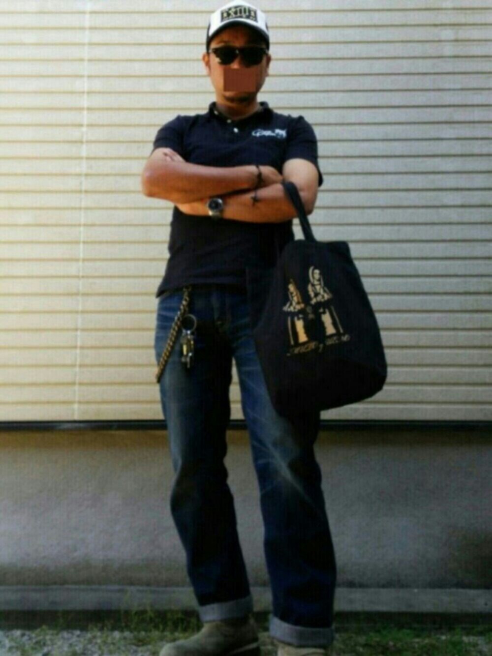 ブラック系のトートバッグ、ブラック系のポロシャツ、ベージュ系のブーツを着用したメンズの春コーディネートの1枚目の写真