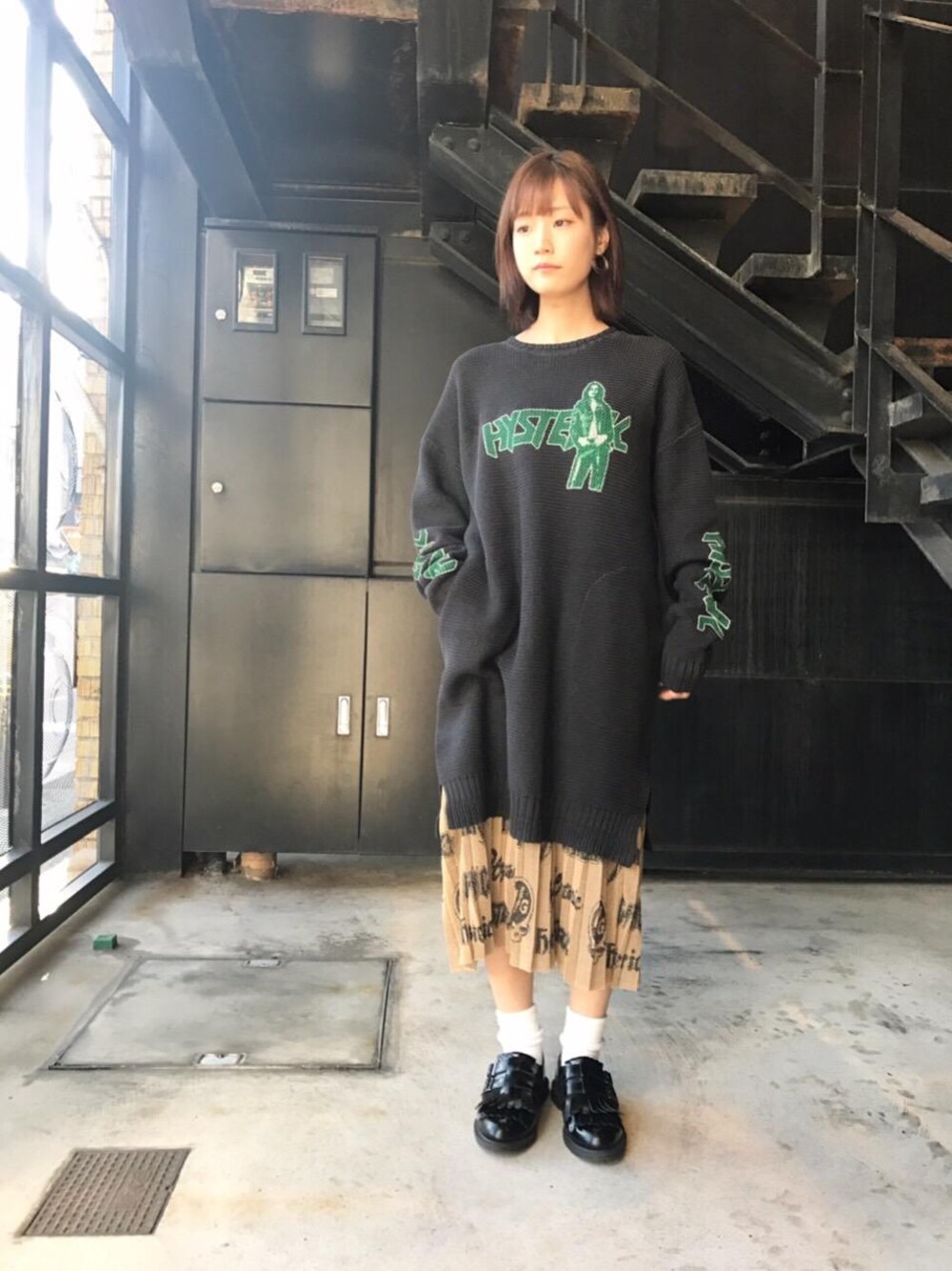 ゴールド系のスカート、ブラック系のワンピースを着用したレディースの秋コーディネートの1枚目の写真
