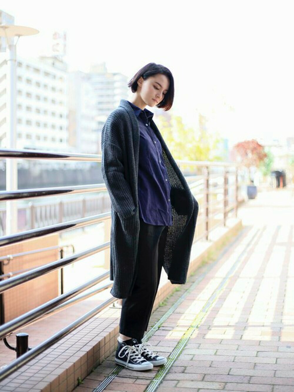 ブラック系のカーディガン/ボレロ、ブルー系のシャツ/ブラウス、ブラック系のチノパンツを着用したレディースの冬コーディネートの1枚目の写真