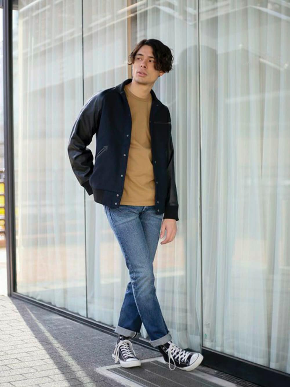 ブルー系のスタジャン、ブラウン系のTシャツ/カットソー、ブルー系のデニムパンツを着用したメンズの冬コーディネートの1枚目の写真