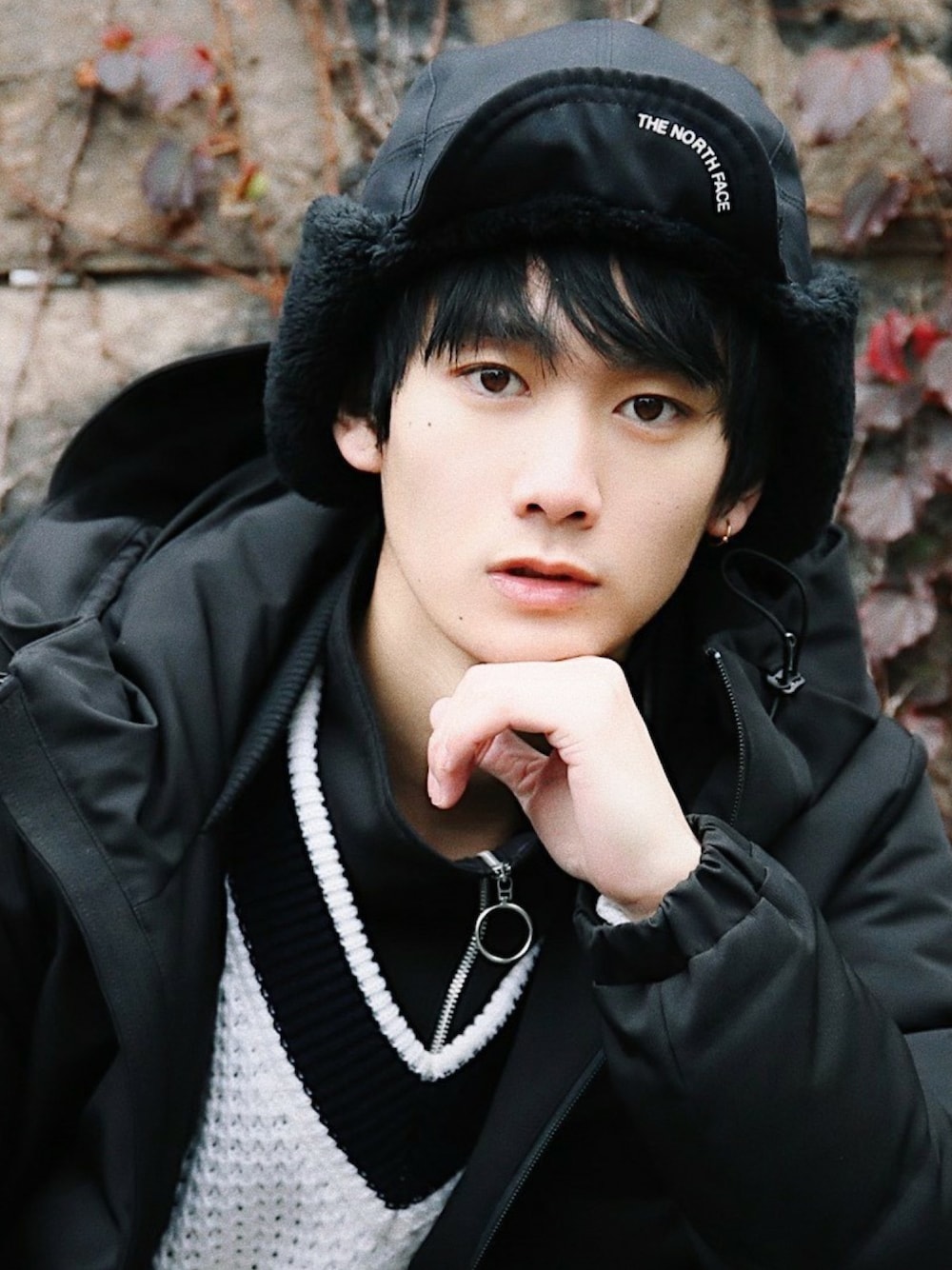 ブラック系のダウンジャケット/コート、ホワイト系のニット/セーター、ブラック系のキャップを着用したメンズの冬コーディネートの1枚目の写真