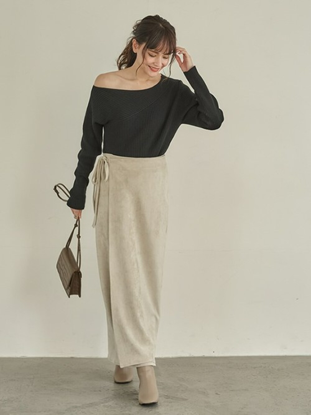 ブラック系のニット/セーター、ベージュ系のスカート、ベージュ系のブーツを着用したレディースの冬コーディネートの1枚目の写真