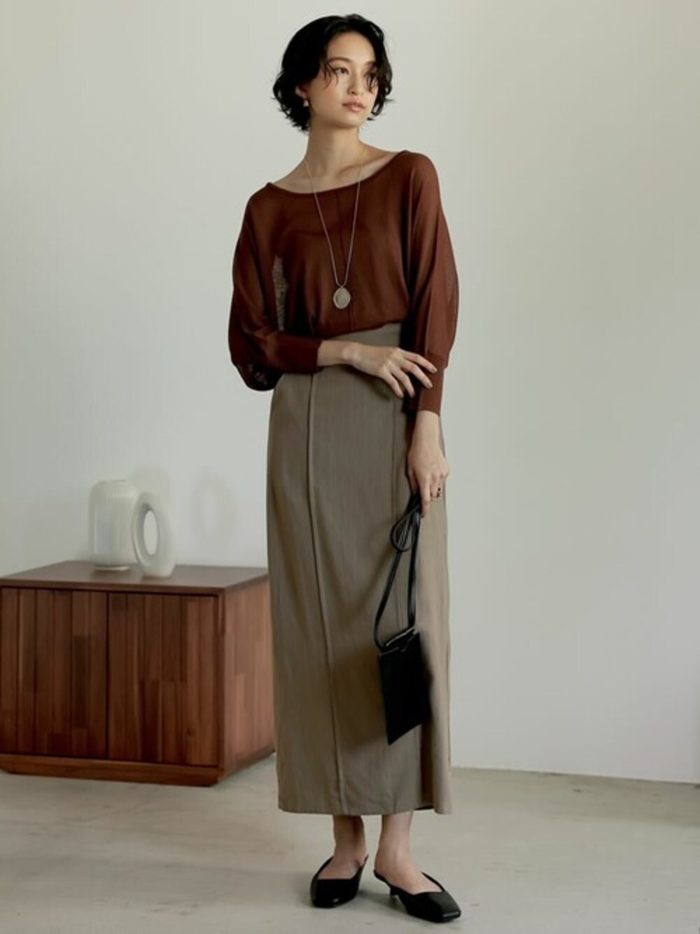 ブラウン系のニット/セーター、ブラウン系のスカート、ブラック系のサンダルを着用したレディースの夏コーディネートの1枚目の写真