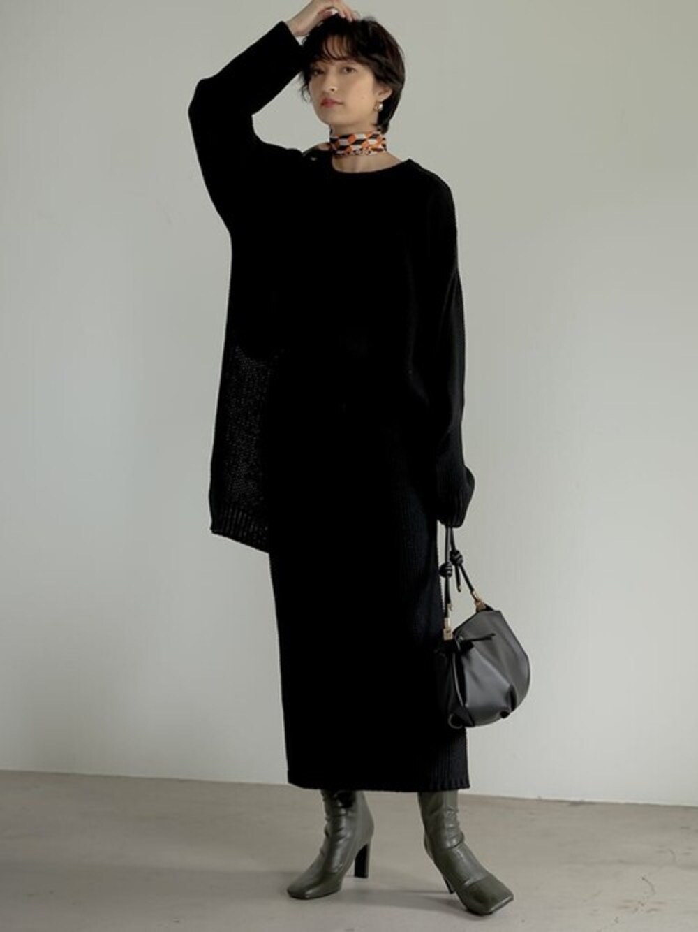 ブラック系のニット/セーター、ブラック系のスカート、グリーン系のブーツを着用したレディースの秋コーディネートの1枚目の写真