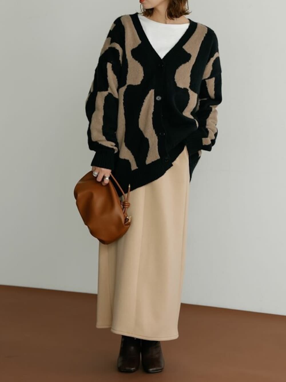 ブラック系のカーディガン/ボレロ、ベージュ系のスカート、イエロー系のショルダーバッグを着用したレディースの冬コーディネートの1枚目の写真