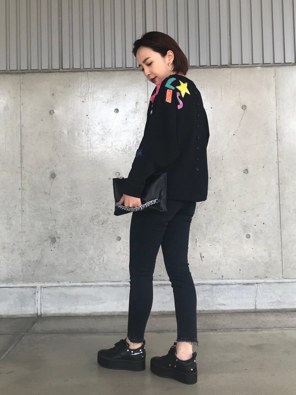 ブラック系のスウェット、ブラック系のデニムパンツ、ホワイト系のスニーカーを着用したレディースの秋コーディネートの1枚目の写真