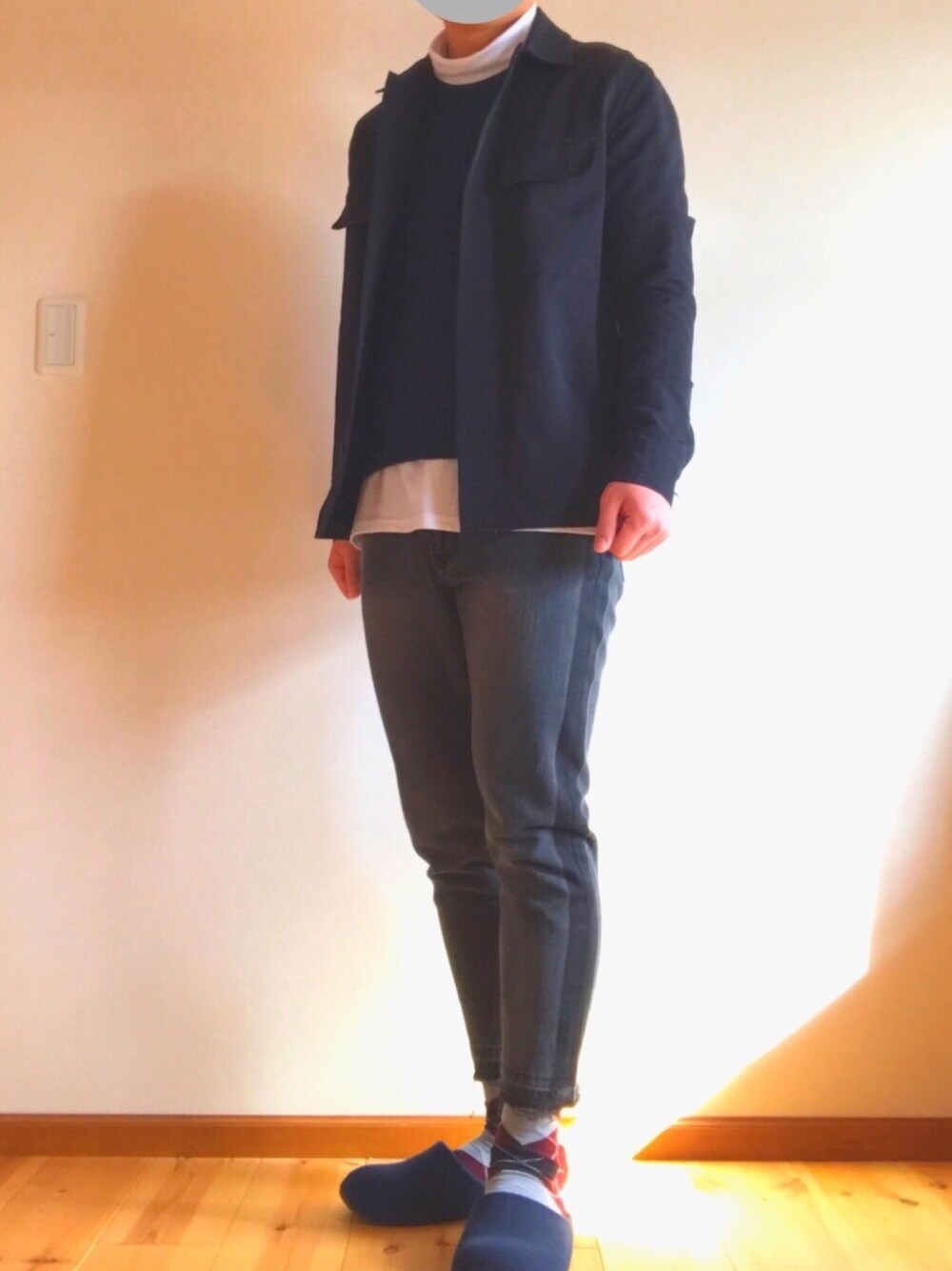 ブラック系のデニムパンツ、ブルー系のニット/セーター、ホワイト系のTシャツ/カットソーを着用したメンズの冬コーディネートの1枚目の写真