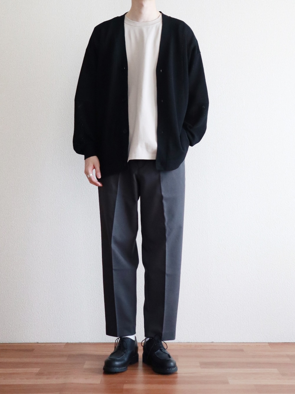 ブラック系のカーディガン/ボレロ、グレー系のスラックス、ベージュ系のTシャツ/カットソーを着用したメンズの春コーディネートの1枚目の写真