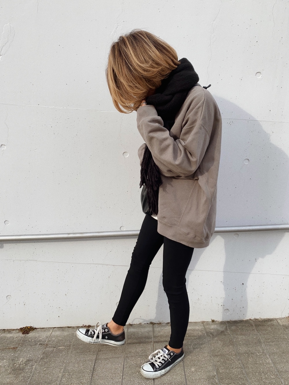 グレー系のスウェット、ブラック系のショルダーバッグ、ブラック系のマフラーを着用したレディースの冬コーディネートの1枚目の写真