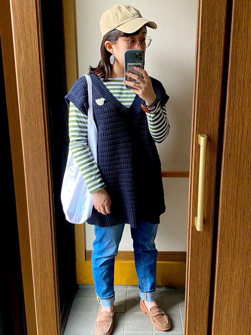 ブルー系のベスト、グリーン系のTシャツ/カットソー、ブルー系のデニムパンツを着用したレディースの春コーディネートの1枚目の写真