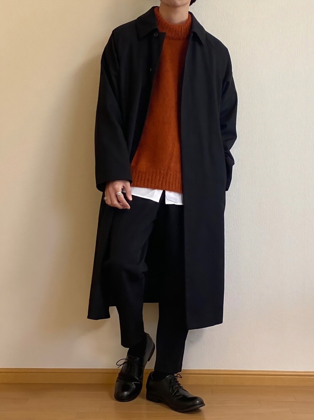 ブラック系のステンカラーコート、レッド系のニット/セーター、ホワイト系のシャツ/ブラウスを着用したメンズの秋コーディネートの1枚目の写真