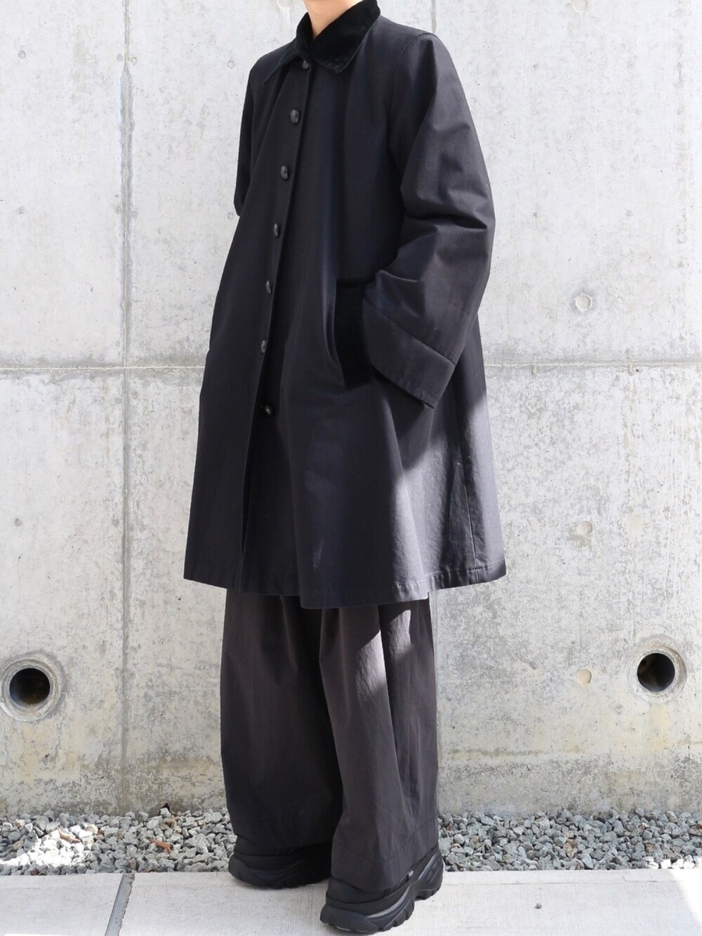 ブラック系のステンカラーコート、ブラック系のその他パンツ、ブラック系のスニーカーを着用したメンズの冬コーディネートの1枚目の写真