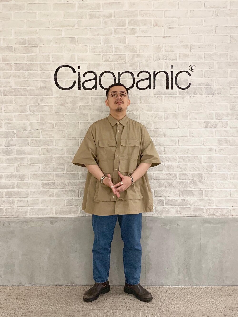 ブルー系のデニムパンツ、ベージュ系のシャツ/ブラウス、ブラウン系のブーツを着用したメンズの夏コーディネートの1枚目の写真