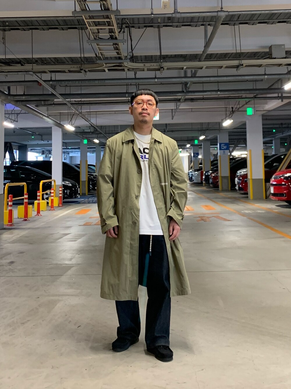 ブラック系のステンカラーコート、ブルー系のデニムパンツ、ホワイト系のTシャツ/カットソーを着用したメンズの春コーディネートの1枚目の写真