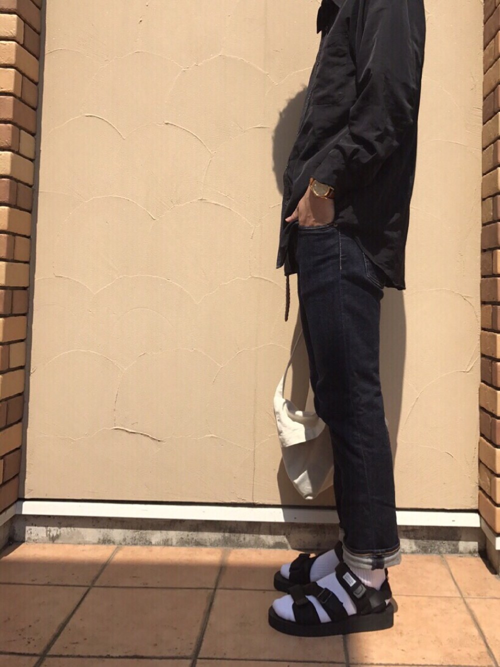ブルー系のデニムパンツ、ブラック系のサンダル、ブラック系のシャツ/ブラウスを着用したメンズの夏コーディネートの1枚目の写真