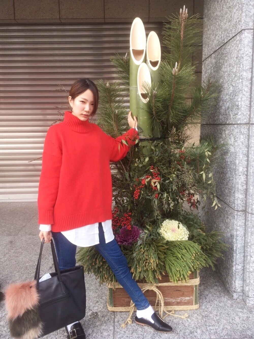レッド系のニット/セーター、ブルー系のデニムパンツ、ピンク系のマフラーを着用したレディースの冬コーディネートの1枚目の写真