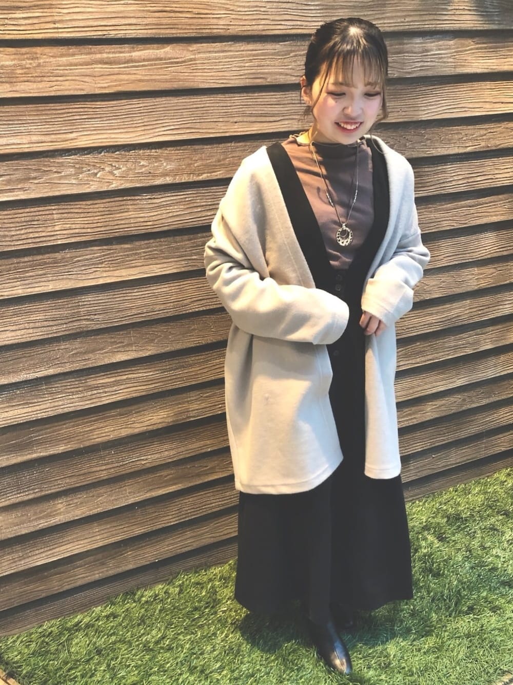 ブラウン系のTシャツ/カットソー、ブラック系のスカート、ベージュ系のノーカラーコートを着用したレディースの冬コーディネートの1枚目の写真