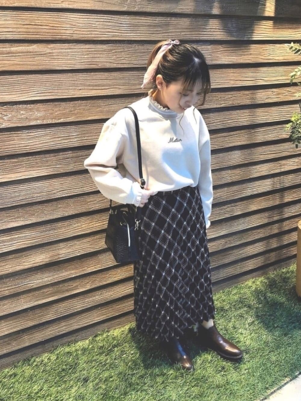 ベージュ系のスウェット、ブラック系のショルダーバッグ、ブラック系のスカートを着用したレディースの冬コーディネートの1枚目の写真