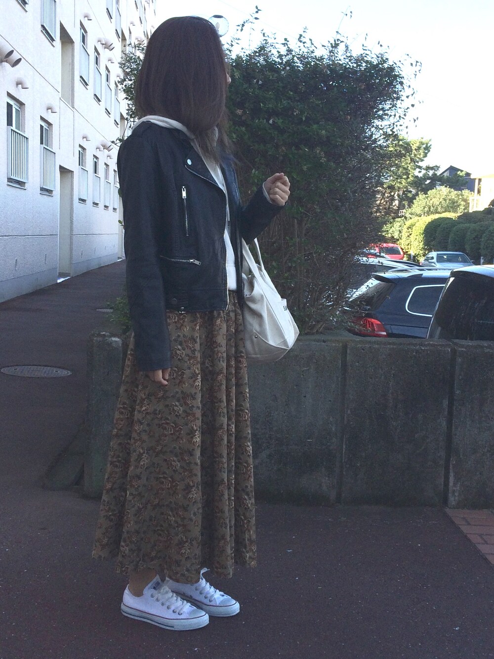 ベージュ系のトートバッグ、ホワイト系のスニーカー、ブラック系のライダースジャケットを着用したレディースの秋コーディネートの1枚目の写真