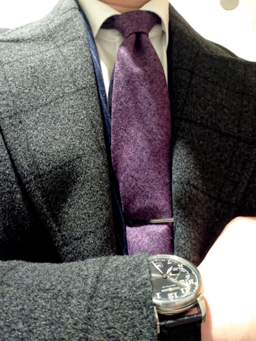 シルバー系のネクタイピン、パープル系のネクタイ、グレー系のアナログ腕時計を着用したメンズの冬コーディネートの1枚目の写真