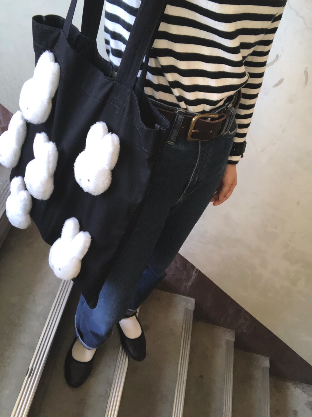 ブルー系のデニムパンツ、ブラック系のバレエシューズ、ブラック系のトートバッグを着用したレディースの秋コーディネートの1枚目の写真