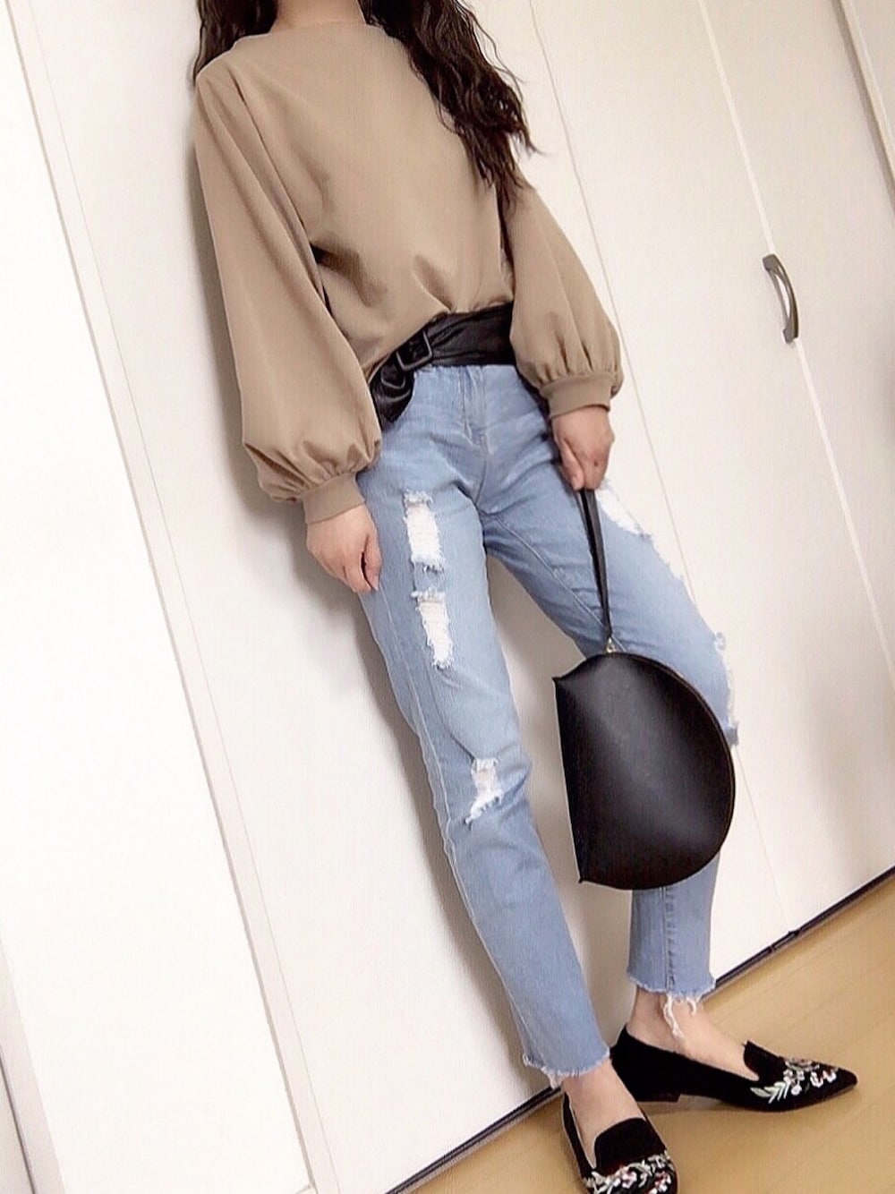 ブラウン系のスウェット、ブルー系のデニムパンツ、ブラック系のパンプスを着用したレディースの春コーディネートの1枚目の写真
